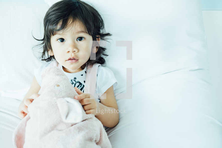 toddler girl lying on a bed 