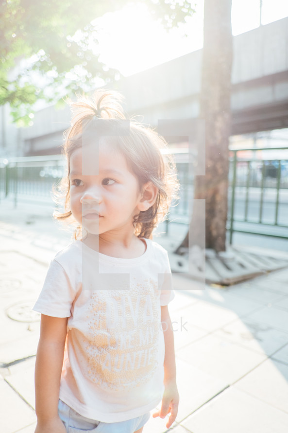 a little girl standing on a sidewalk 