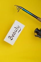 A fishing pole with a piece of paper with the word beauty on it 