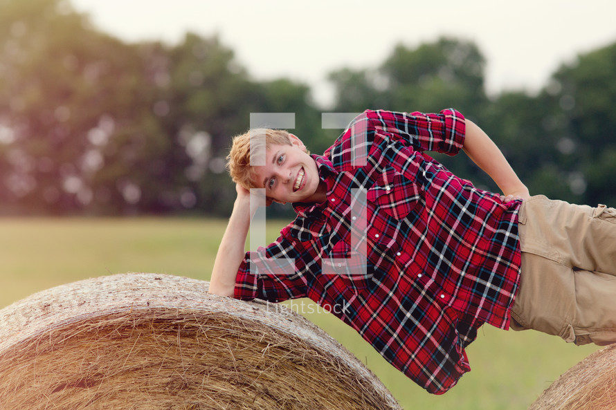 teen boy lying on hay bales