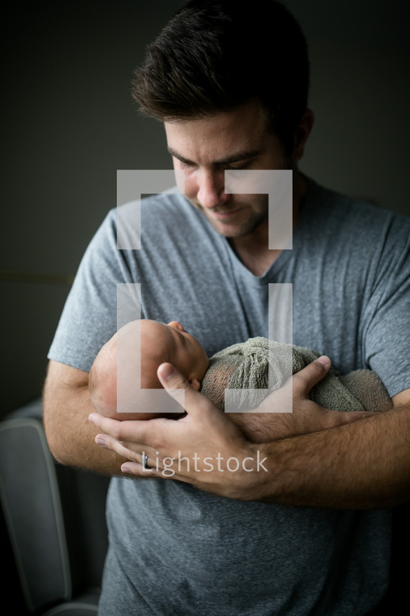 father holding a swaddled newborn 