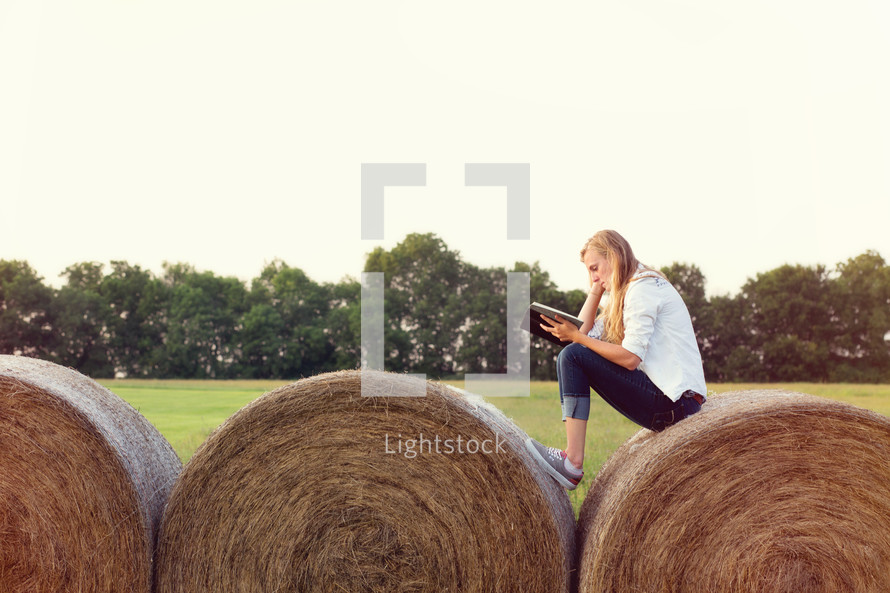 woman reading a Bible on hay bales 