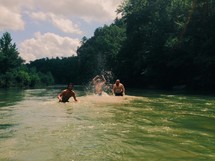 man splashing and swimming in a mountain river