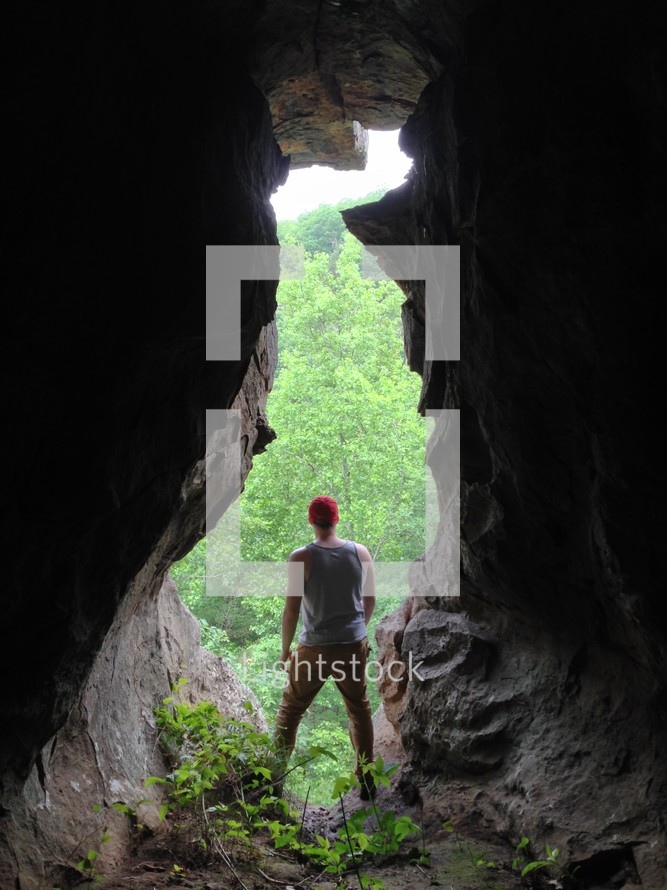 man standing at the entrance of a cave