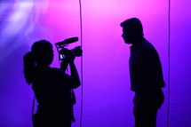 silhouette of woman with a video camera and a man 