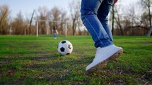 Boy kicking a football on a green meadow. Child dream of football match. Sports training in park. Child playing soccer outdoor.