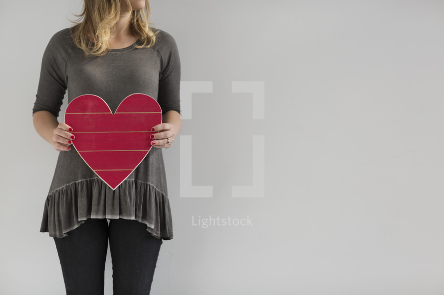 a woman holding a wooden heart 