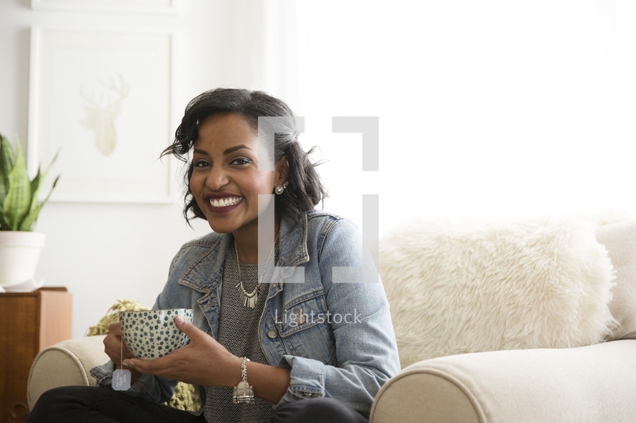 an African American woman holding a cup of hot tea 