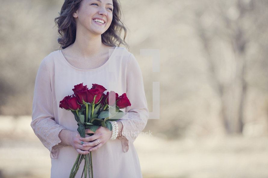 woman holding a bouquet of red roses outdoors 