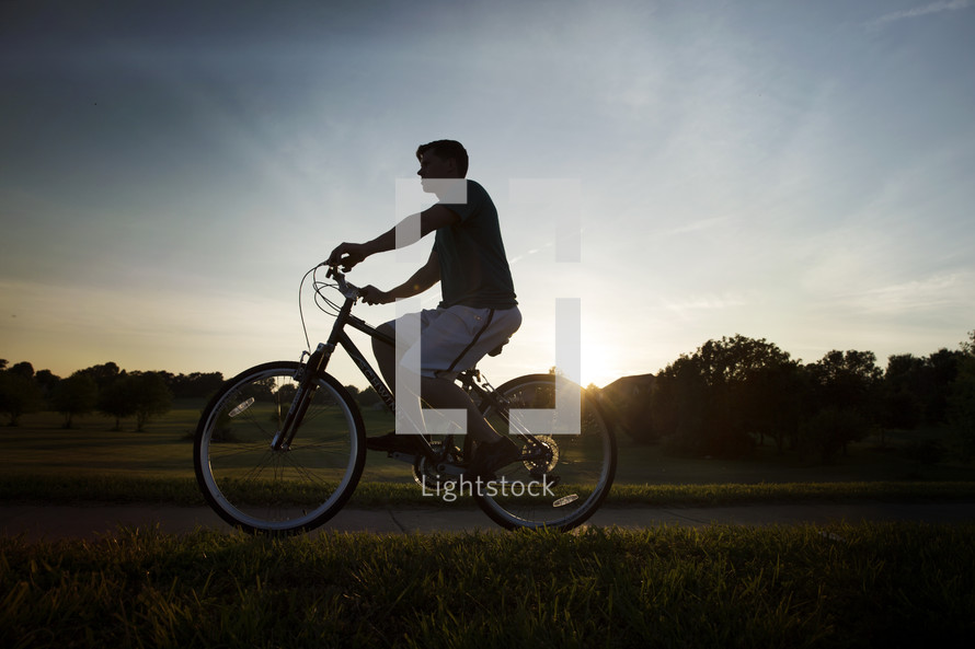 man riding a bicycle at sunset 