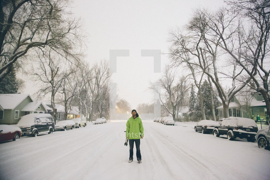 man standing in the middle of a snow covered road 