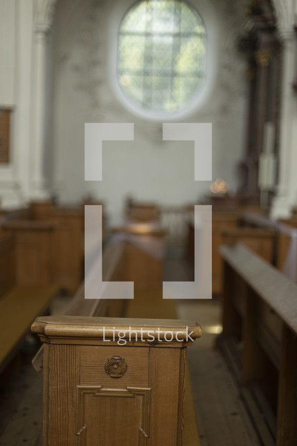 Oval, ornate window over a pew