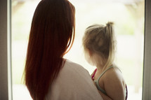 a mother and daughter looking out a window 