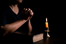 Bible and candlelight with praying hands