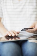 a woman holding a credit card and shopping online.