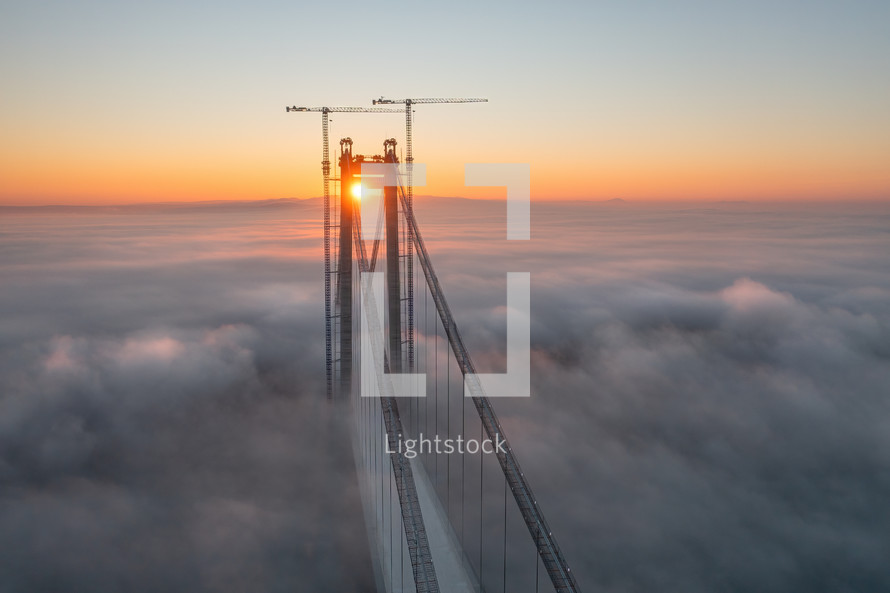 Aerial view of bridge through clouds at sunset
