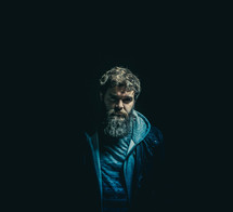 man with a thick beard standing in darkness 