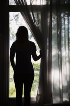 silhouette of a woman looking out a window 
