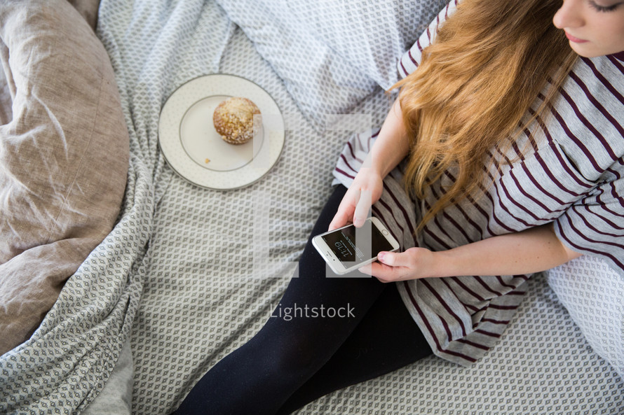 girl sitting on a bed texting 