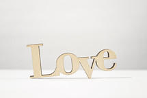 A wooden word "love" with a white and light grey background