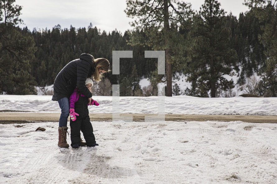 mother and child in a snowsuit playing outdoors 