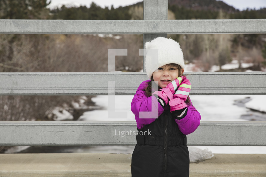 a little girl in a snowsuit and mittens 