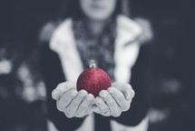 girl holding a red Christmas ornament 