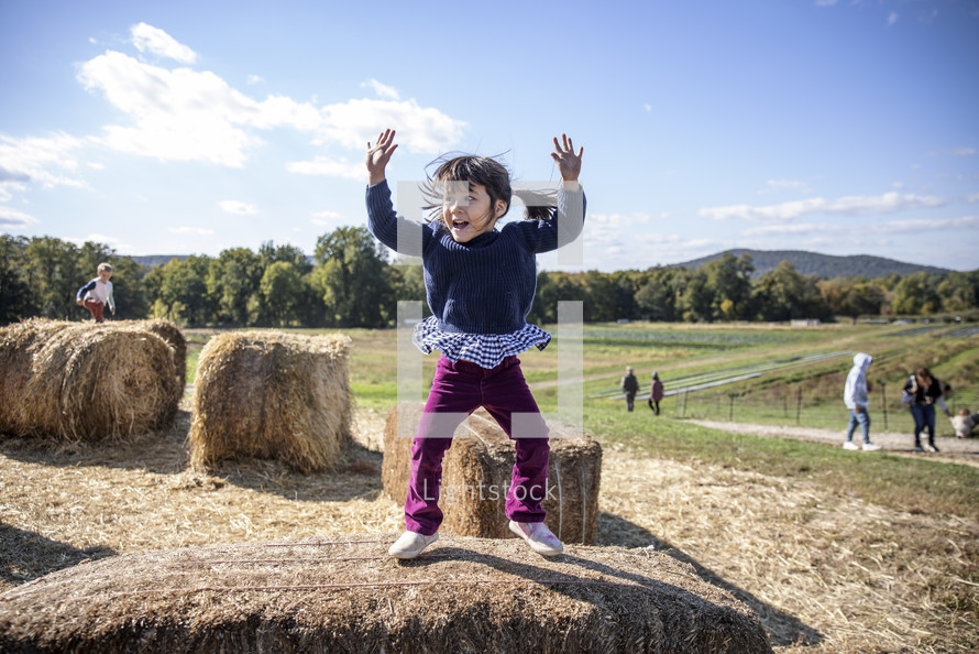 Little girl jumping on the hay
