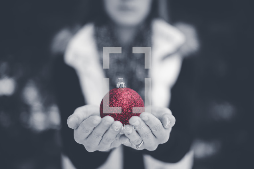 girl holding a red Christmas ornament 