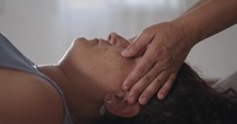 Shiatsu treatment. Masseuse treating a woman's neck and face during treatment