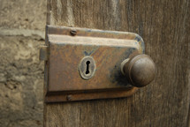 A rusty doorknob and lock on an old wooden door.