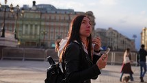 Pretty woman and takes photos on a phone, first time in big city, traveler life in big city, everyday moment. Mobile phone photography. Backpacker woman visited european city, take photo on cellphone.