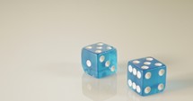 Slow motion macro shot of dice falling and rolling on reflective surface