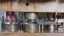 Close up of a punch press forming metal parts in a production line