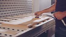 Slow motion of a worker polishing a cabinet door in a furniture factory