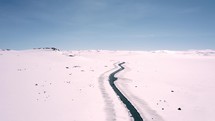 aerial view over a cleared road and snow covered landscape 