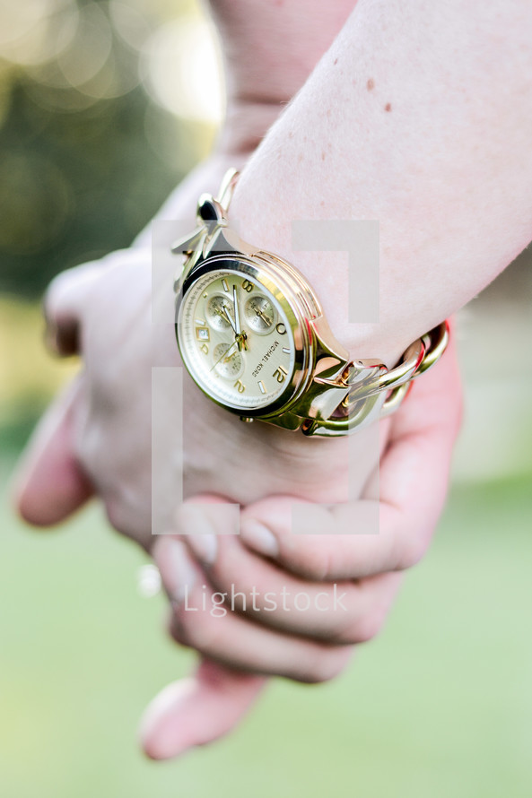 Two hands clasped together and a watch on one wrist.
