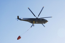 helicopter carrying a bucket of water for firefighting 