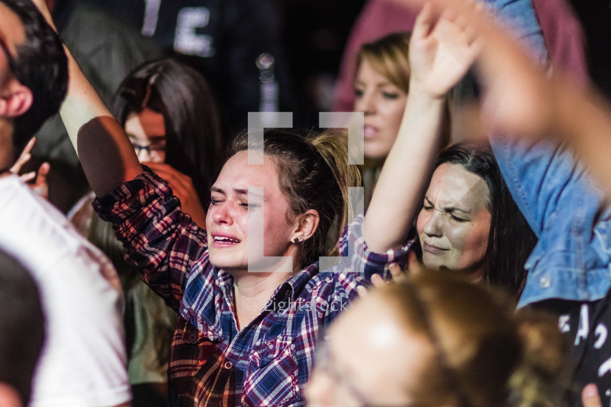 tears streaming down the face of a young woman at a concert 