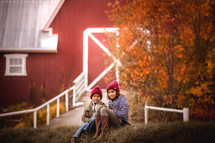 children sitting near a barn 
