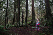 teen girl standing alone in a forest 