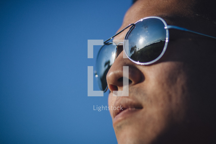 face of a man in sunglasses against a blue sky