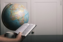 a man reading a Bible and a globe 