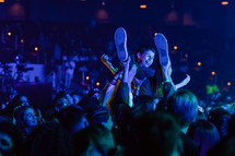 teen boy body surfing at a concert 