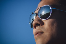 face of a man in sunglasses against a blue sky