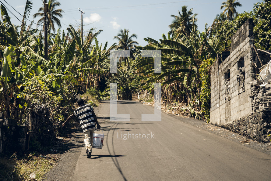 man carrying a bucket on an African street
