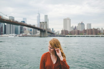 a woman with strawberry blonde hair standing in front of the NYC skyline