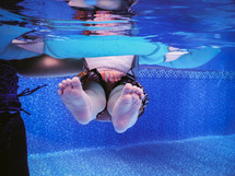 A child being held up in a swimming pool by an adult.