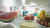 POV shot from inside a refrigerator of kids opening the door and taking out food