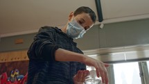 Corona pandemic boy with face mask using hand sanitizer to prevent coronavirus